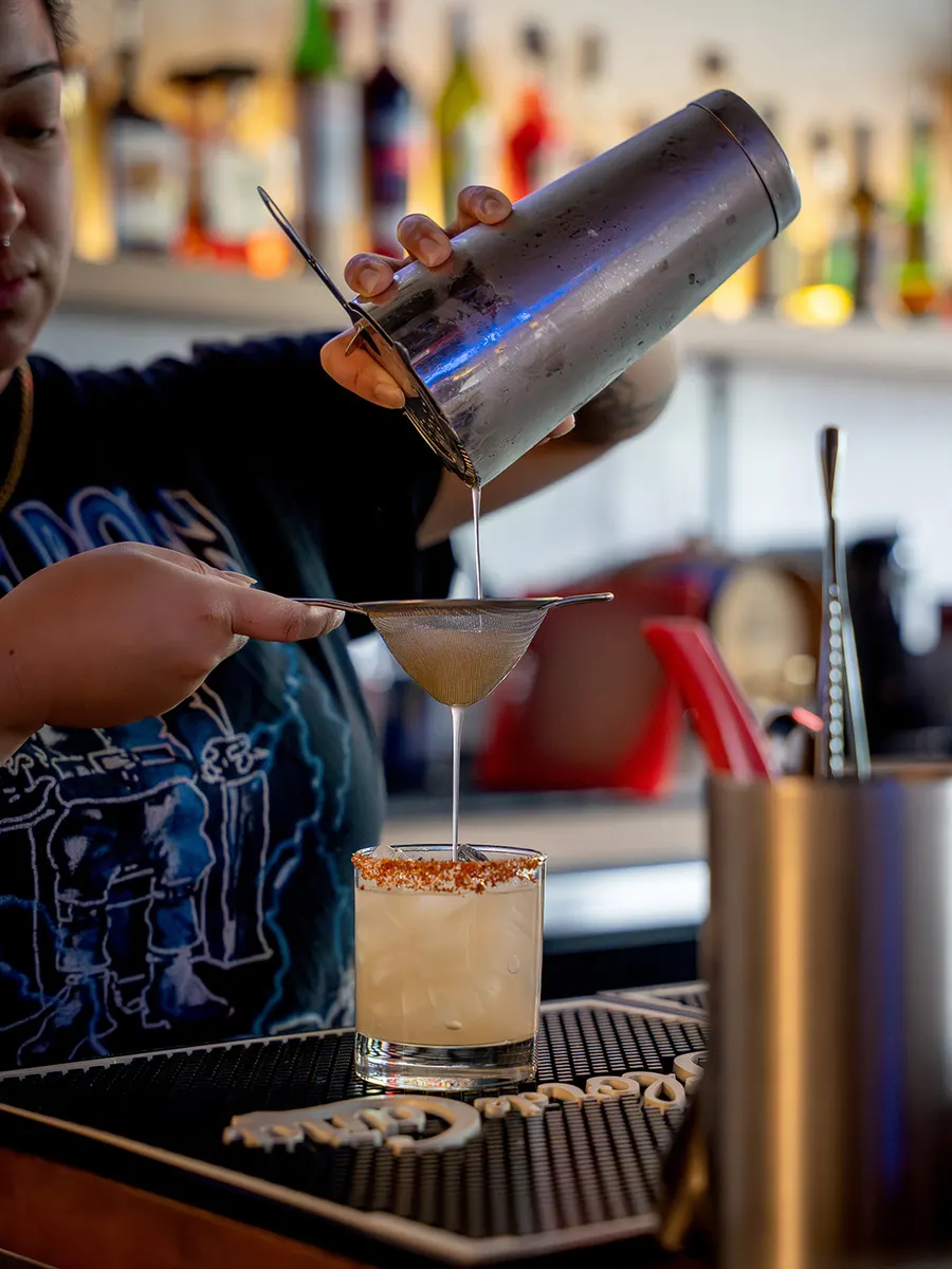Our bartender straining a fresh cocktail at the bar