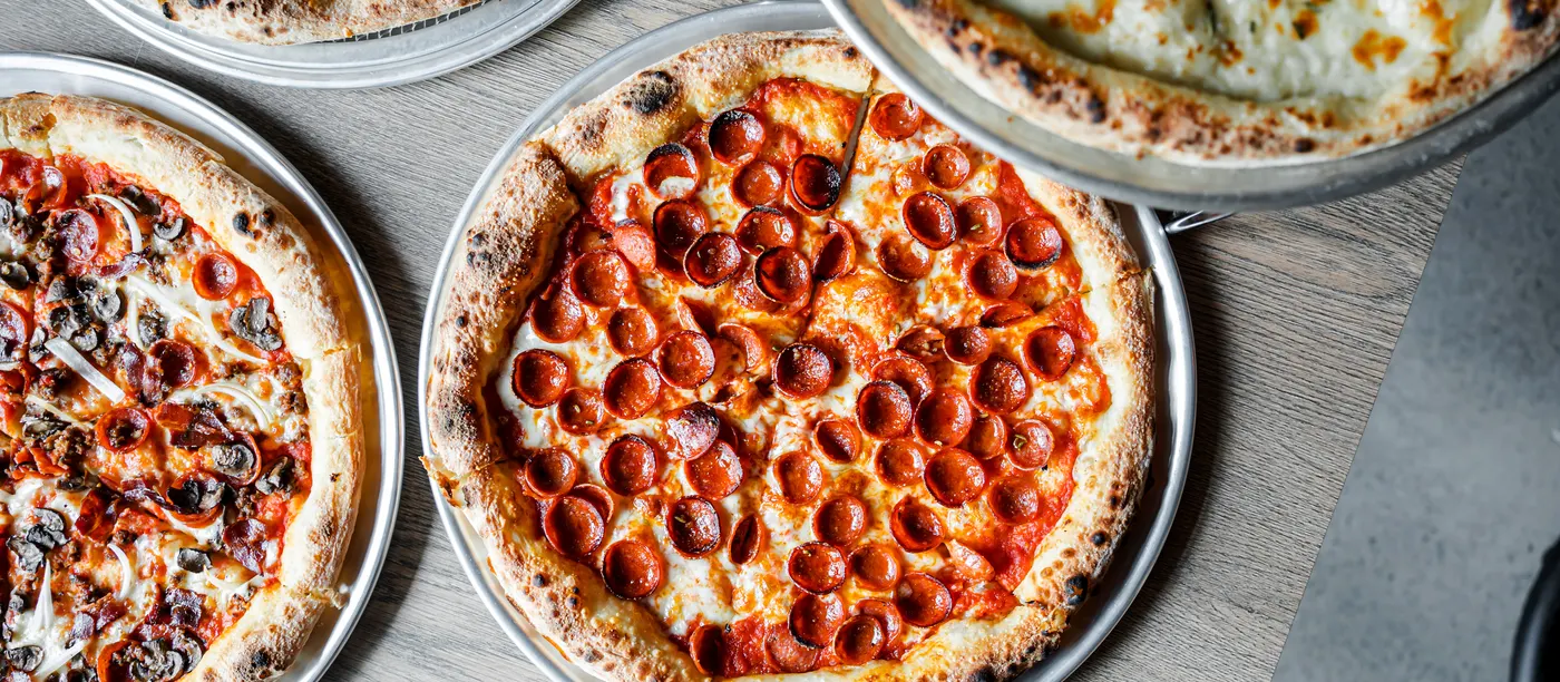 An overhead spread of Brooklyn-style pizzas on the table